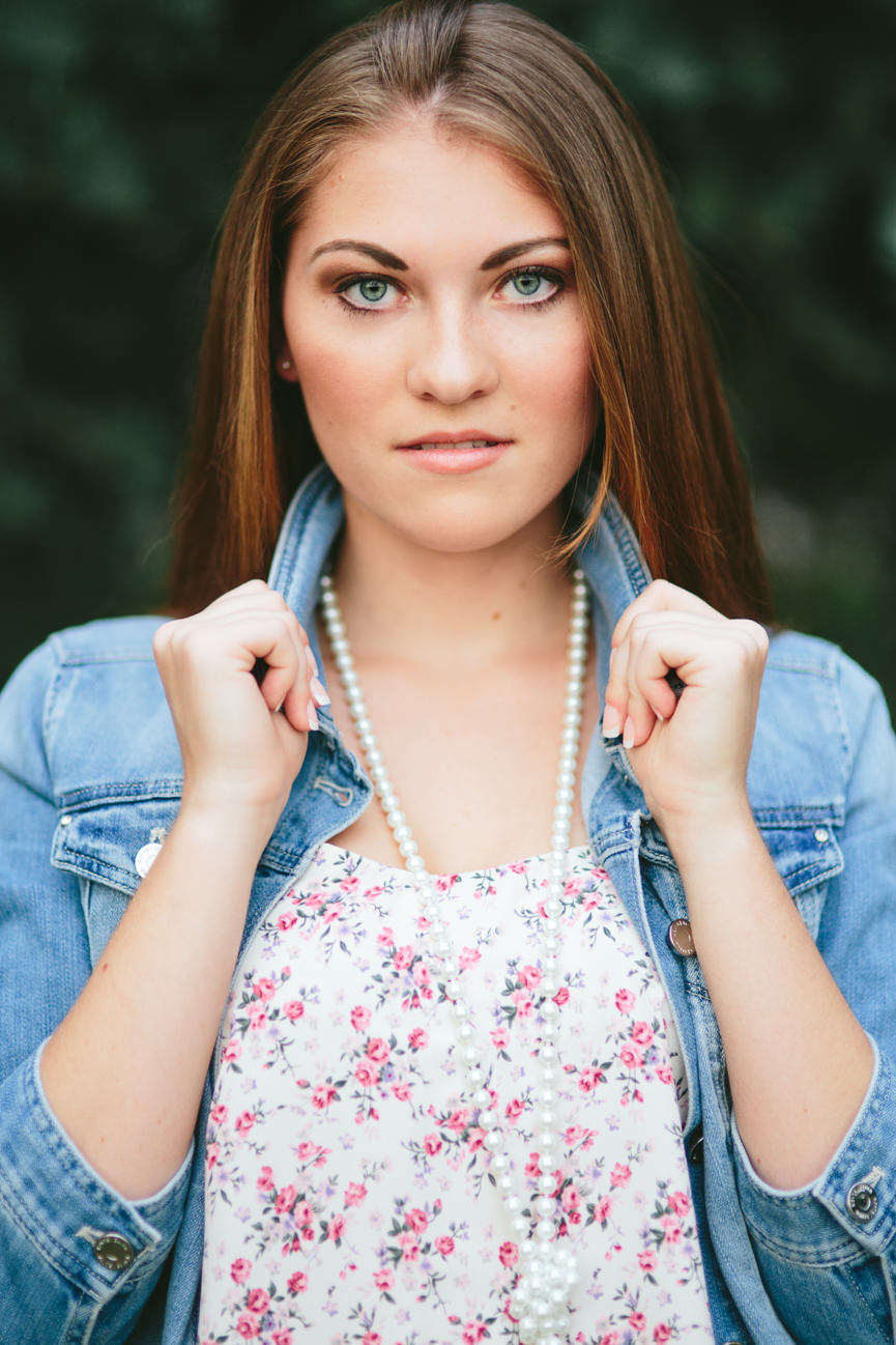 A young woman wearing a jean jacket poses for her headshots in Missoula Montana